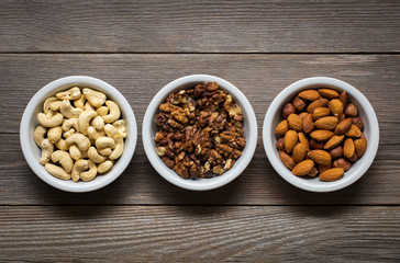 Sorted nuts in white bowls on wooden background 