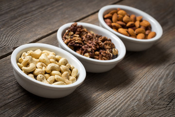 Sorted nuts in white bowls on wooden background 