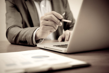 Fototapeta premium Businessman analyzing investment charts with laptop. Accounting