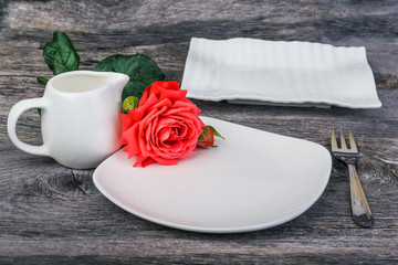 dishes, milk jug and rose on the rustic wooden table