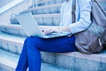 Naklejka premium Young woman using laptop on steps outdoors