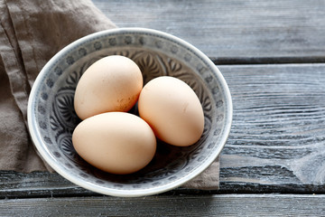 Fresh eggs in a bowl on wooden boards