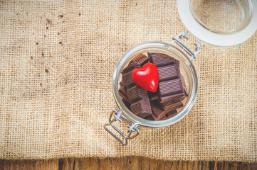 Chocolate and heart in a jar on a wooden background on the day o