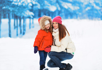Happy mom and child having fun in winter snowy day