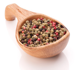 Black, green and pink pepper peppercorn mix in wooden spoon isol