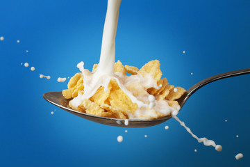 milk splashing into spoon full of cornflakes