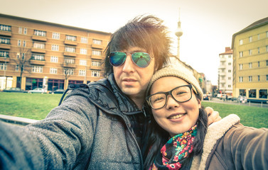 Hipster multiracial couple of tourists taking a selfie in Berlin