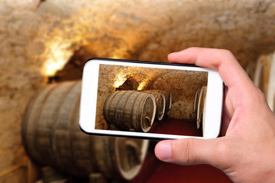Hands taking photo old wine barrels with smartphone.