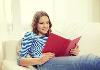 smiling teenage girl reading book on couch