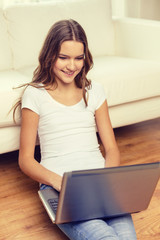 smiling teenage girl with laptop computer at home