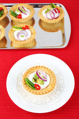 Tartlets with greens and vegetables with sauce on plate and