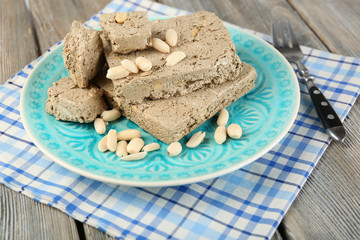 Sunflower halva with peanuts on plate, on wooden background