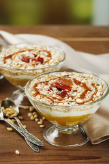 Tasty dessert with oat flakes and honey, on table