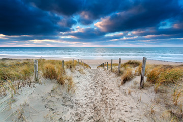 chemin de sable vers la côte de la mer du Nord au coucher du soleil