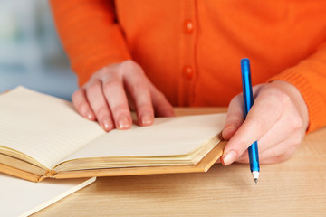 Female hand with pen, notebook and diary at wooden desktop