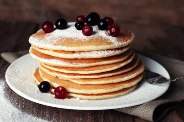Stack of delicious pancakes with powdered sugar and berries