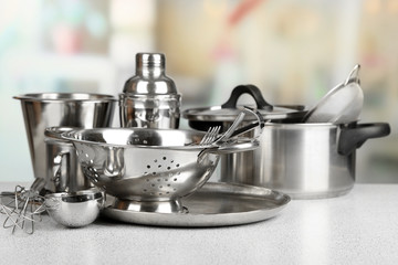 Stainless steel kitchenware on table, on light background