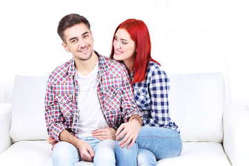 Young couple sitting together in sofa in room