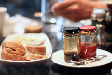 Delicious breakfast, toasts and fruity jam in jars on the plates