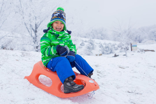 Little boy having fun with sled in winter park
