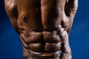 Close-up of abdominal muscles bodybuilder on a blue background