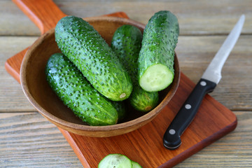 Fresh cucumbers in a clay bowl on cutting board