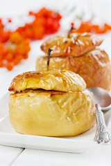 baked apples with honey, raisins, curds and nuts in a white plate decorated ashberry on a wooden background