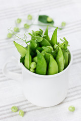 green peas in a white cup on a linen napkin