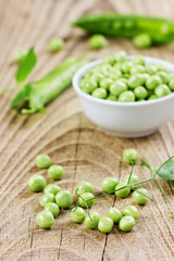 green split peas in a white cup on a rustic wooden background