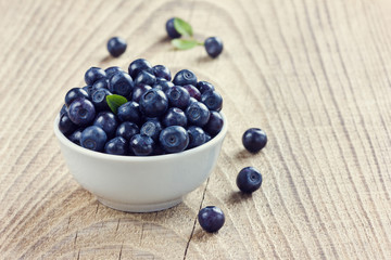 blueberries in the white bowl on a wood rustic background