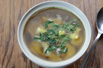 Bowl of chicken broth with noodles.
