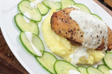 Closeup of roasted piece of chicken on mashed potatoes.