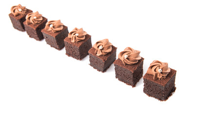Bite sized chocolate cake with icing on top over white
