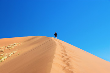 Fototapeta na wymiar Man on dunes of Namib desert, Namibia, South Africa
