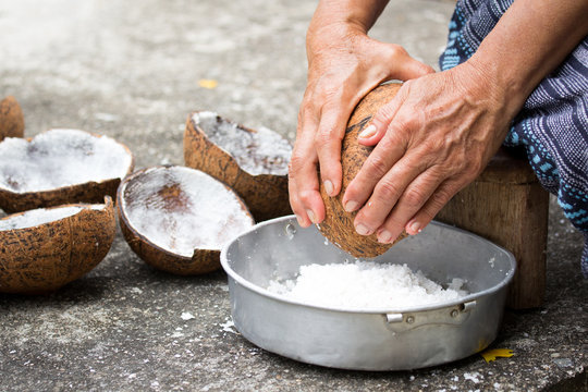 Old woman sit on coconut grater and  grate coconut into bowl