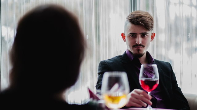 A man with a glass of wine in front of the girl