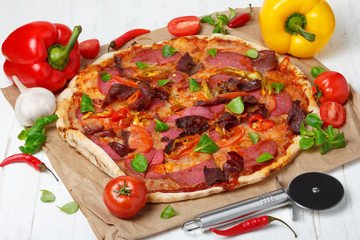 Piiza with a lot of ingredients and pizza cutter knife