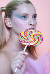 Girl holding a lolly pop, in pink background