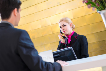 Rezeptionistin checkt Mann bei Anreise im Hotel ein