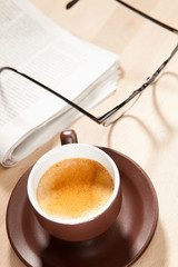 Eine Tasse Kaffee mit Zeitung und Brille