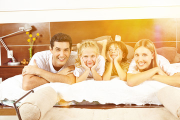 Glückliche Familie liegt im Bett mit Kindern