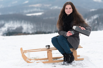Two girlfriends sledge downhill in winter