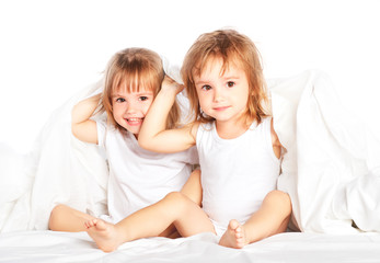 happy little girls twins sister in bed having fun