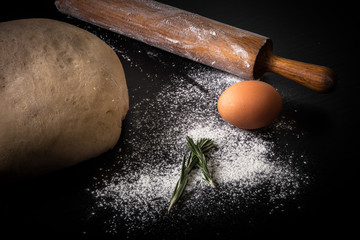 Flour, rolling pin, egg, rosemarin and dough for pie. Toned