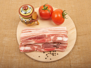 Raw red meat fat bacon and tomato on a wooden board isolation