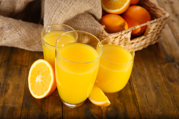 Glass of orange juice with slices and wicker basket with burlap