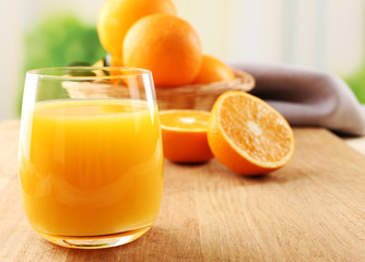 Glass of orange juice and wicker basket with oranges