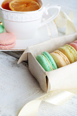 Colorful macaroons with cup of tea on color wooden  background