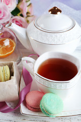 Composition with colorful macaroons, teapot and up of tea