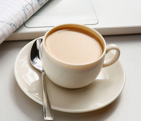 A cup of coffee, paper and a pen on a laptop